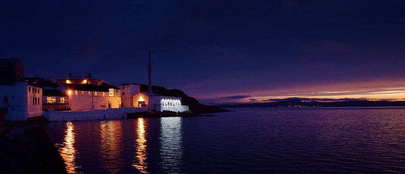 View of Bowmore whisky distillery from the water at sunset.