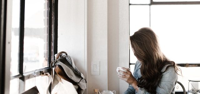 woman drinking from a cup and reading at an office